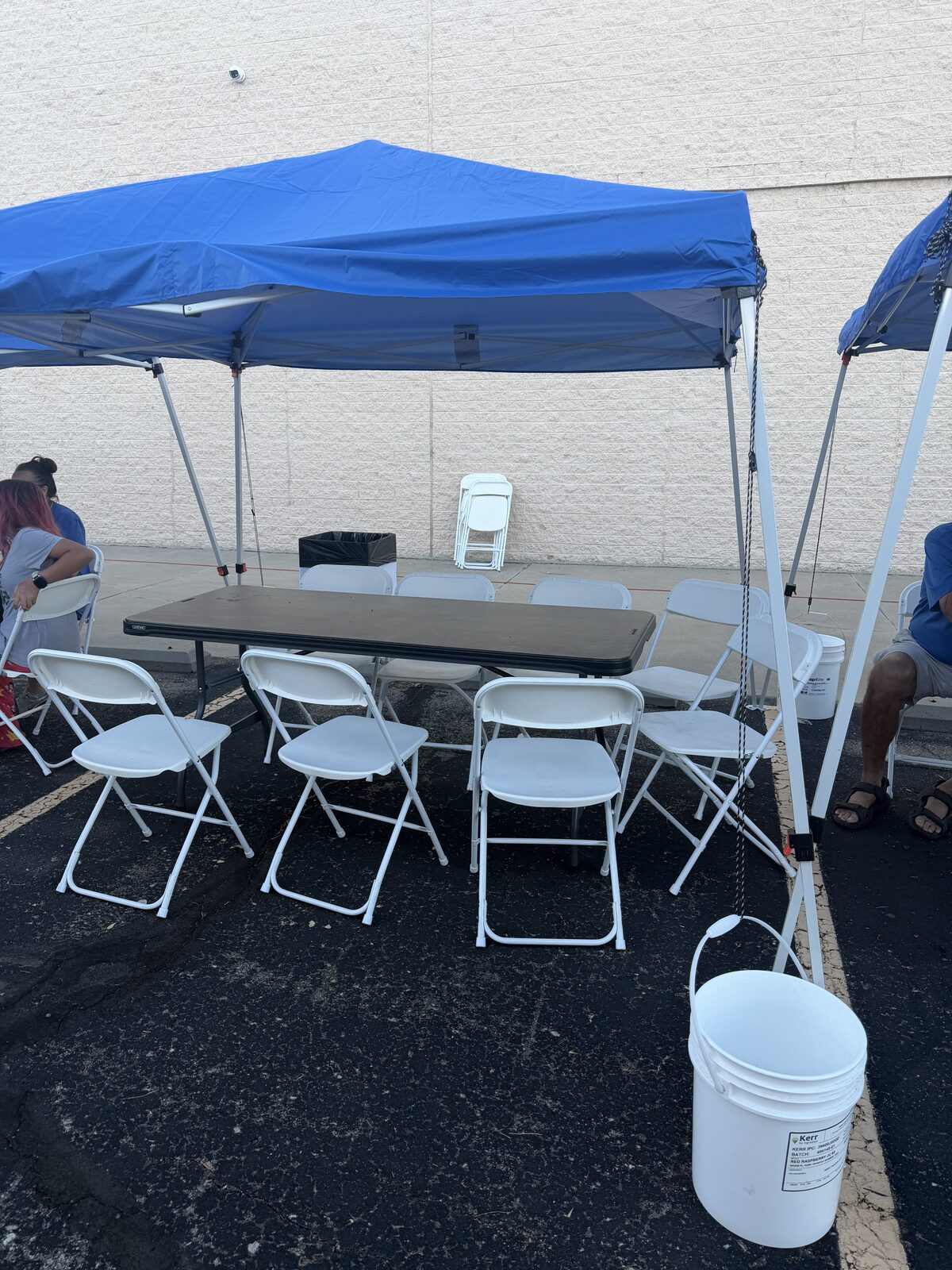 White folding chairs and a banquet table arranged beneath a blue event tent